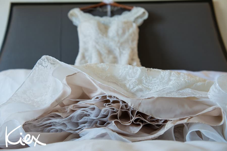 Luxurious wedding dress with intricate lace details and layered tulle fabric, displayed on a bed, ready for a bride's special day.