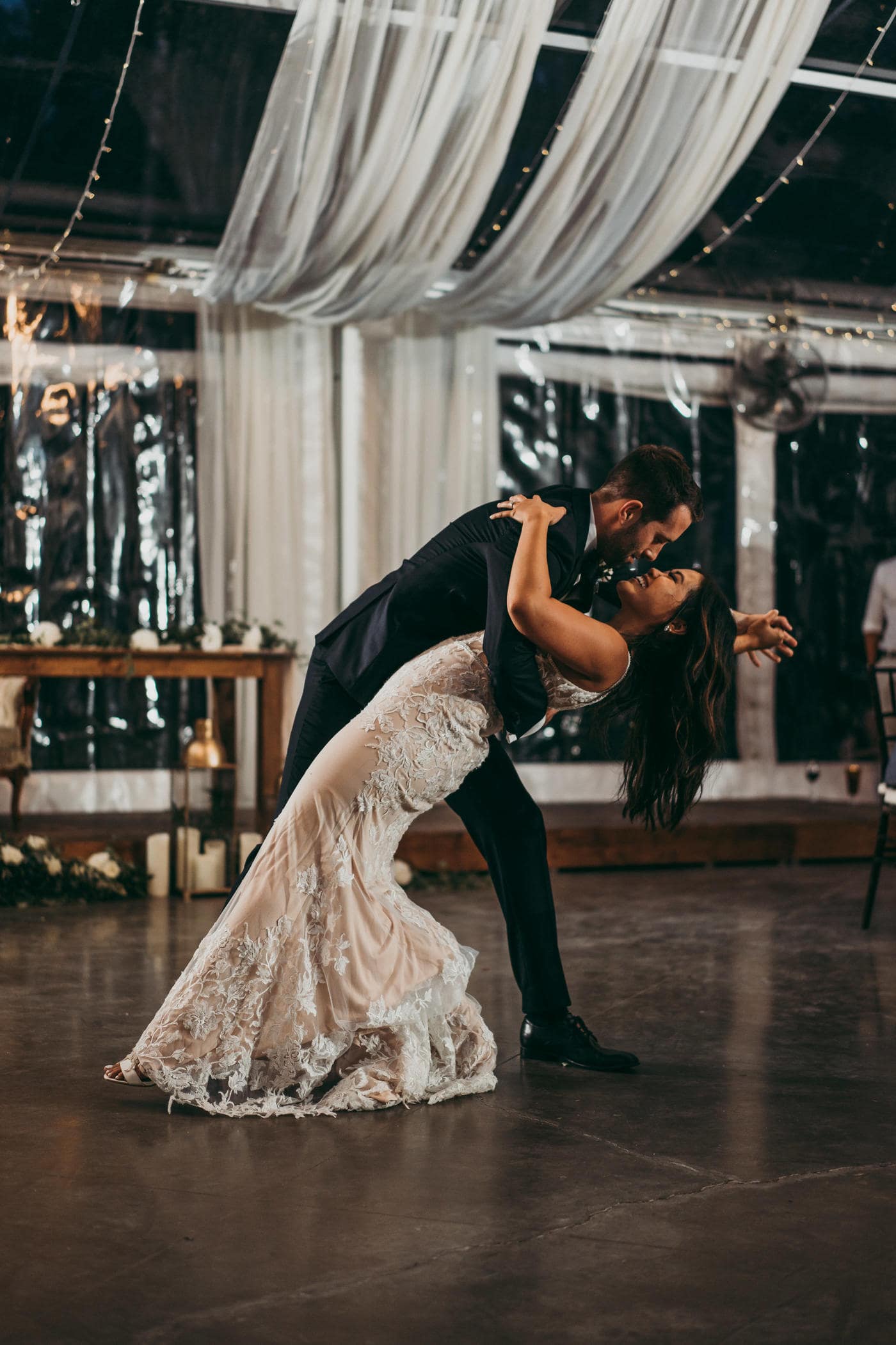 Elegant wedding dance of a bride in lace gown and groom in tuxedo at a decorated Winnipeg wedding venue, soft lighting, romantic atmosphere, wedding celebration.
