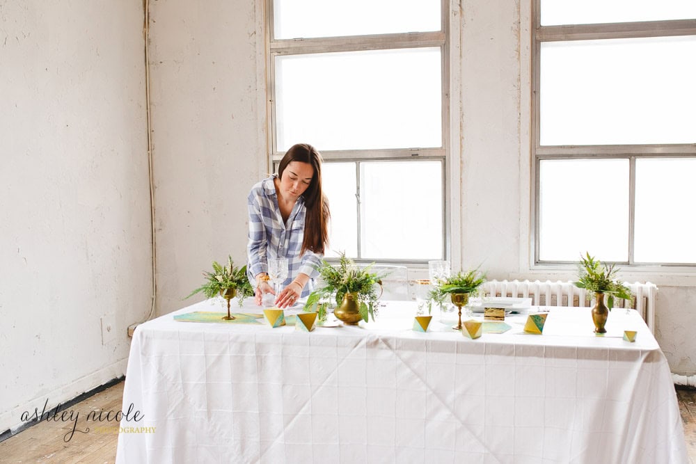 Elegant wedding decor setup with floral arrangements and gold accents on a white tablecloth. Perfect for wedding or event planning in Winnipeg by Melanie Parent Events.