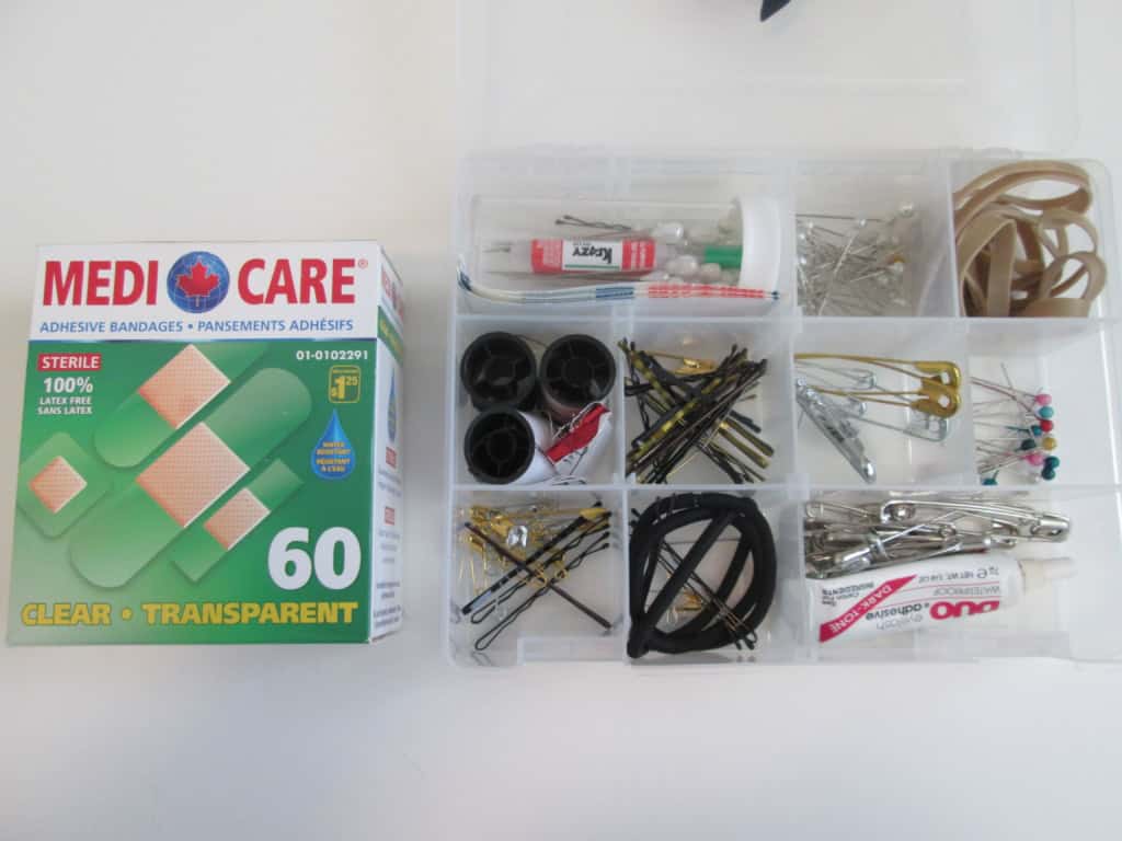 Assorted sewing and craft supplies including pins, bandages, rubber bands, and small tools organized in a plastic container for event decoration or DIY projects.