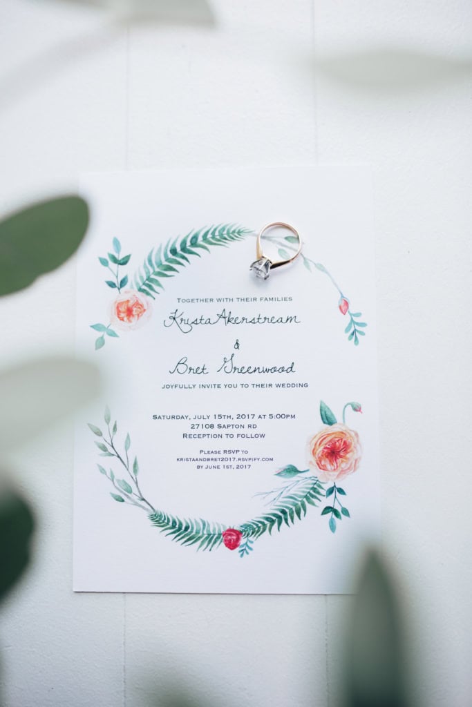 Elegant wedding invitation card with floral design and engagement ring on top, celebrating a wedding in Winnipeg by Melanie Parent Events.