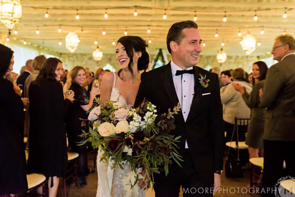 Vibrant wedding reception with bride and groom smiling, surrounded by guests, warm lighting, and elegant decor at Melanie Parent Events in Winnipeg.