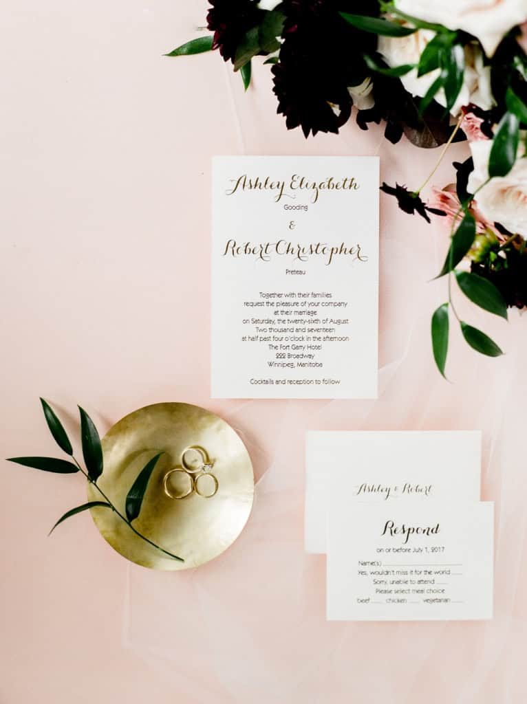 Elegant wedding invitation with gold rings, greenery, and floral decorations for a Winnipeg wedding celebration.