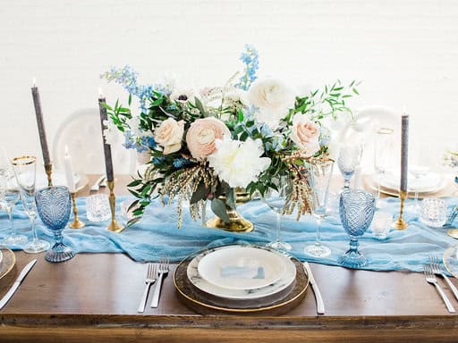 Elegant wedding table setting with blue accents, crystal glasses, and a beautiful floral centerpiece, perfect for Winnipeg wedding and event planning by Melanie Parent Events.