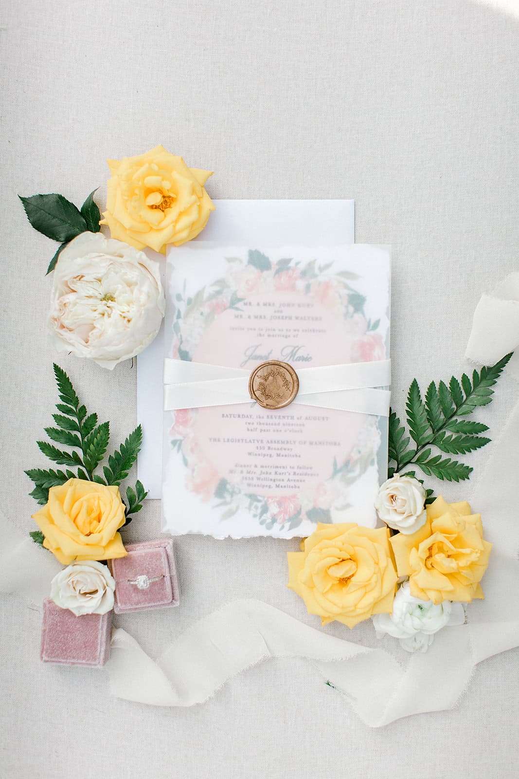 Vibrant yellow and white roses with a wedding invitation and greenery, arranged for a romantic wedding setup in Winnipeg, Manitoba. Perfect for elegant wedding decor and event styling.