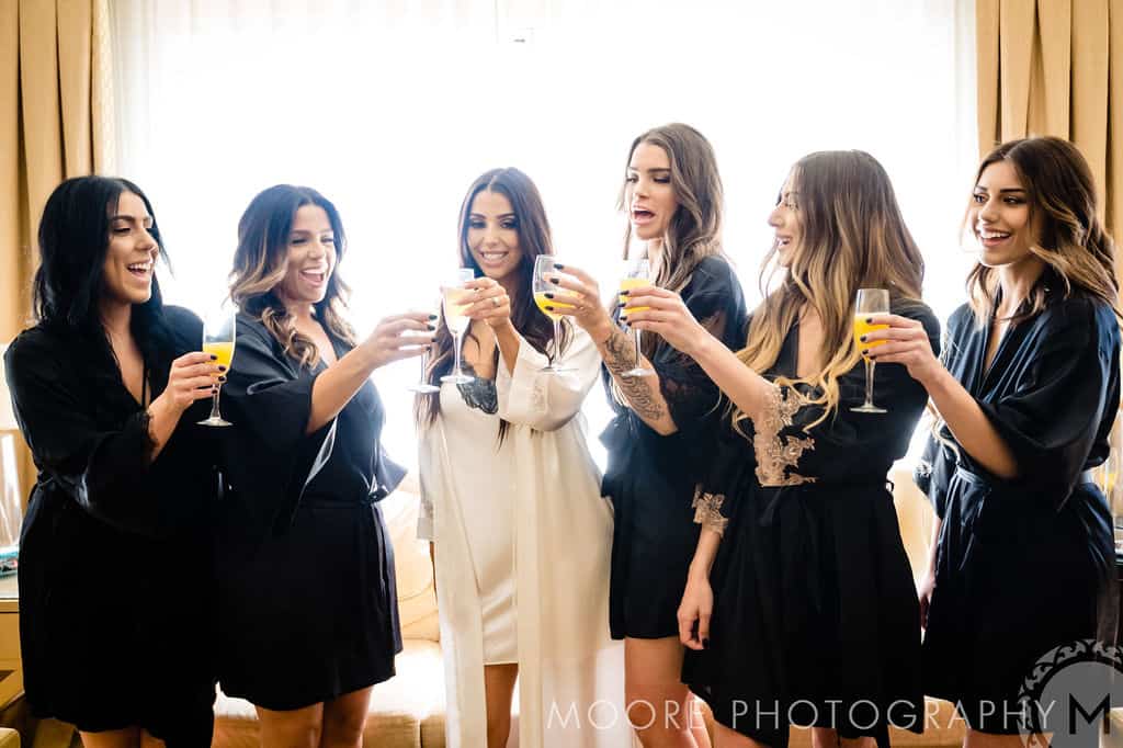 Friends celebrating with mimosas at a bridal party in a luxurious hotel suite in Winnipeg.