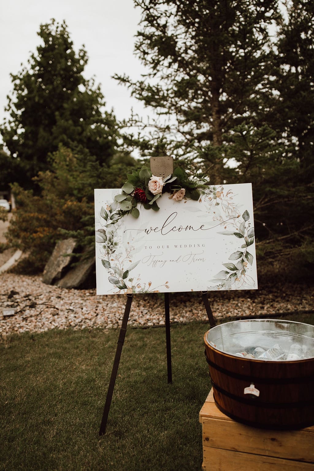 Elegant outdoor wedding welcome sign with floral decorations and greenery in Winnipeg, Manitoba. Perfect for rustic or garden wedding settings.