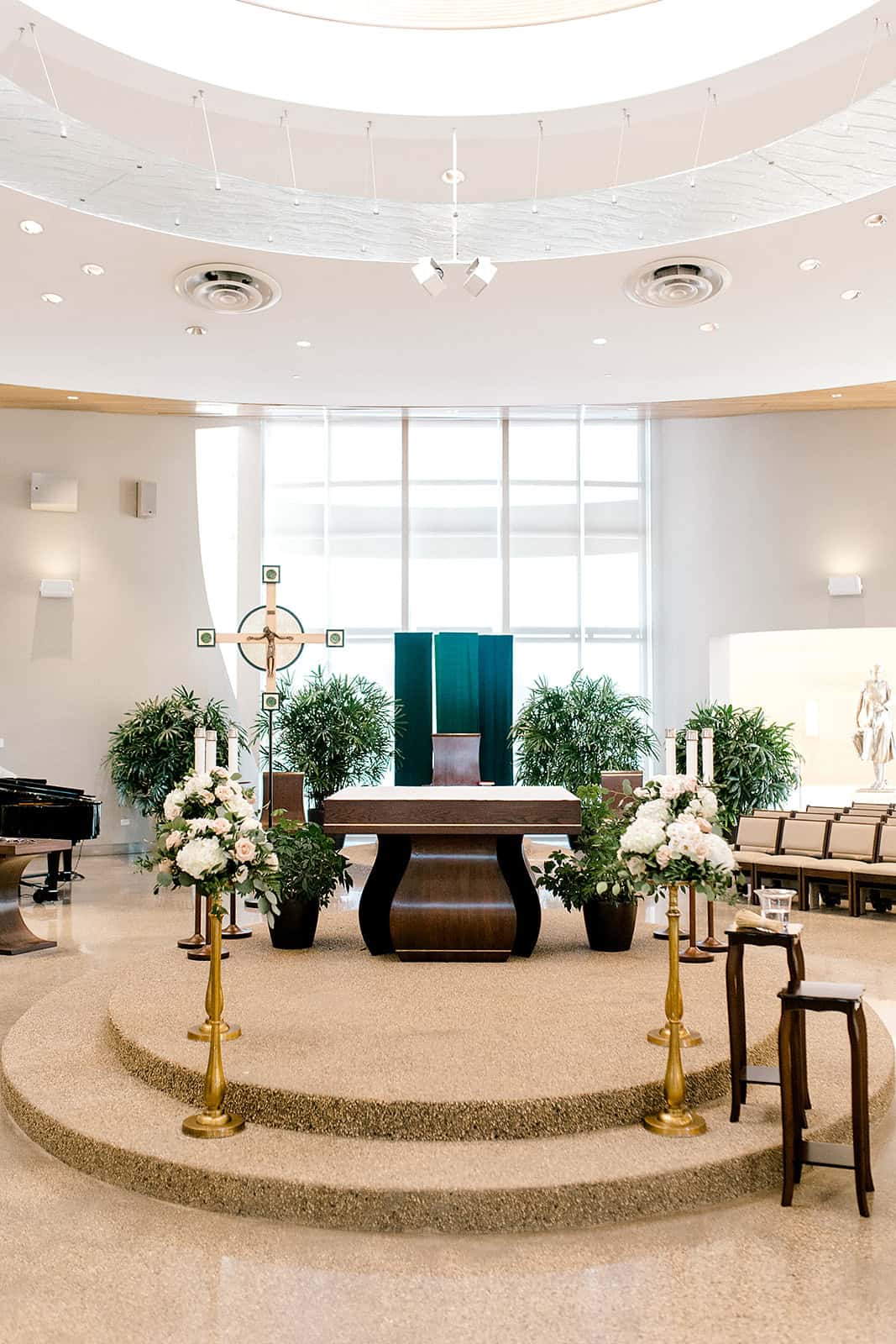 Elegant modern chapel setup with floral arrangements, wooden furnishings, and a cross at the altar, perfect for weddings and religious ceremonies. Bright natural light enhances the serene atmosphere.
