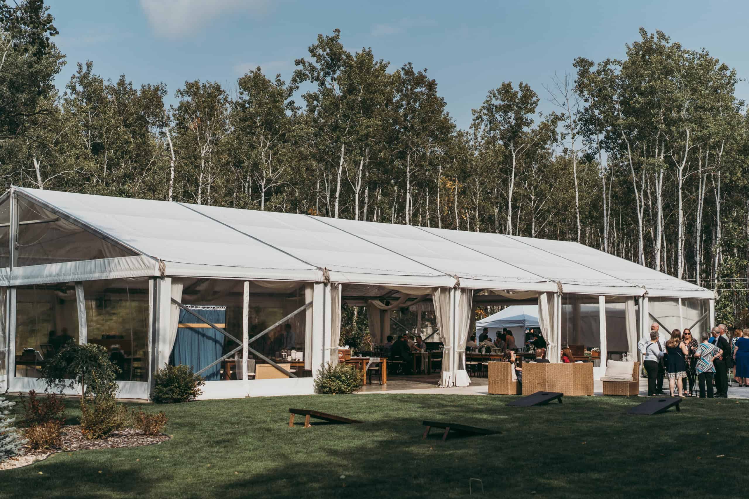 Elegant outdoor event tent setup in a lush green garden with guests mingling, perfect for weddings and special celebrations in Winnipeg.