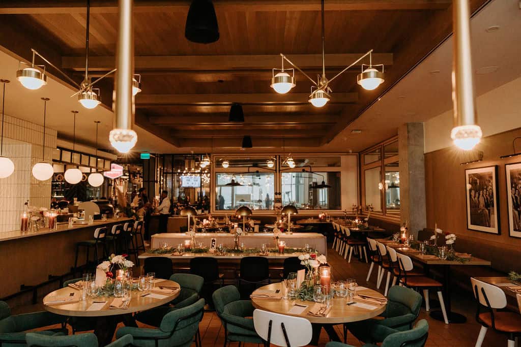 Elegant wedding reception setup with round tables, floral centerpieces, candle lighting, and sophisticated decor in a stylish indoor event space.