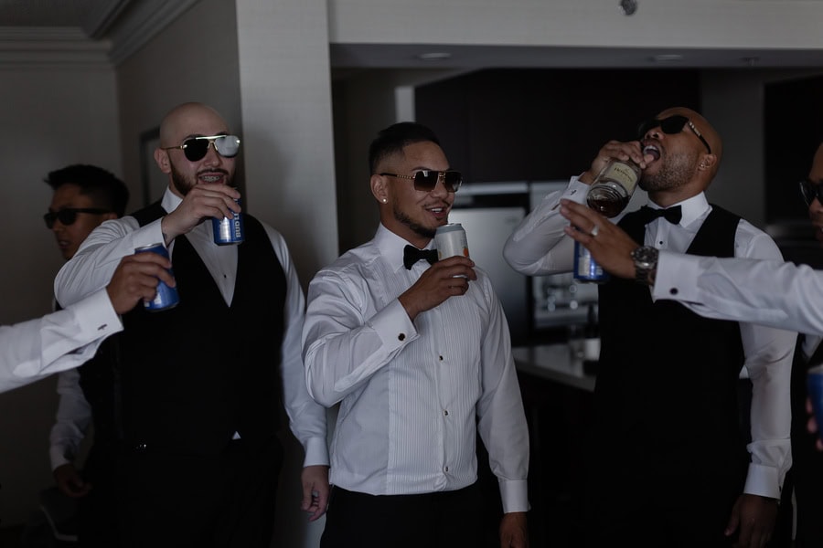 Men in formal attire enjoying drinks at a wedding reception in Winnipeg, celebrating with laughter and camaraderie.