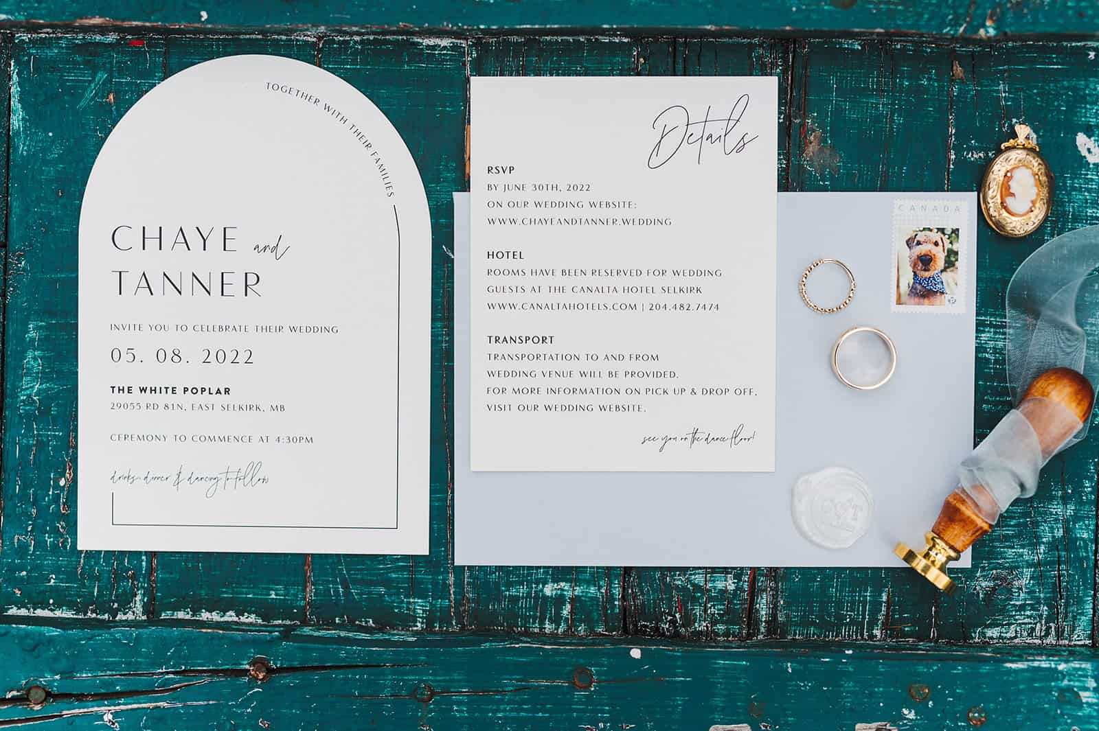 Elegant wedding invitation suite on a rustic wooden table with rings, postage stamp, and wax seal, perfect for Winnipeg wedding and event planning.