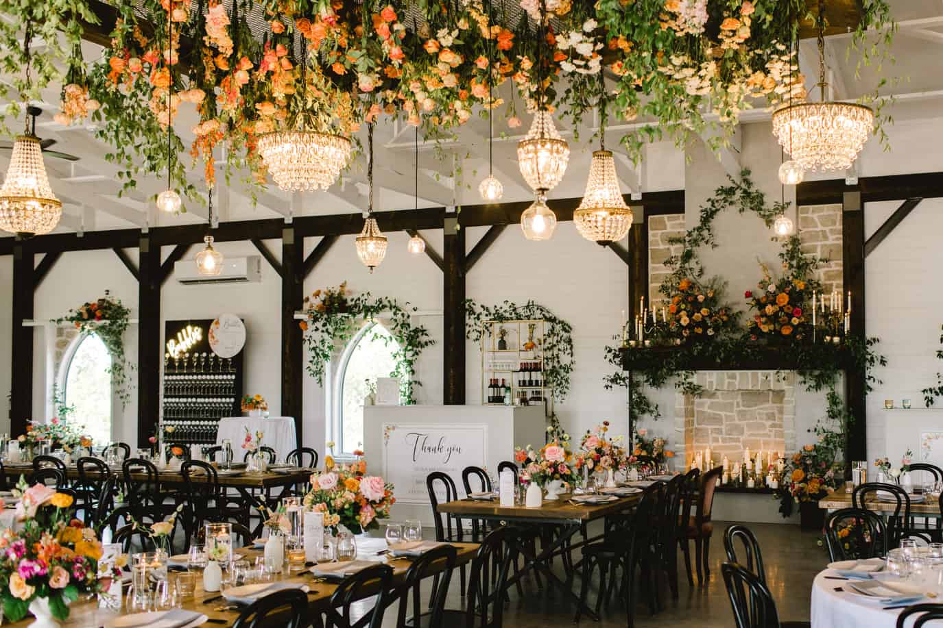 Elegant wedding reception with floral centerpieces, chandeliers, and a cozy fireplace decorated with candles and flowers. Perfect venue for a romantic celebration.