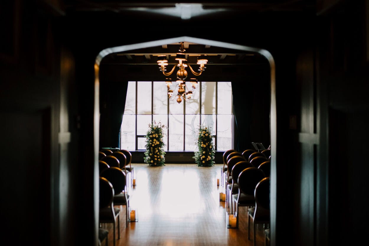 Elegant wedding ceremony setup with floral arrangements and chandelier at Melanie Parent Events in Winnipeg.