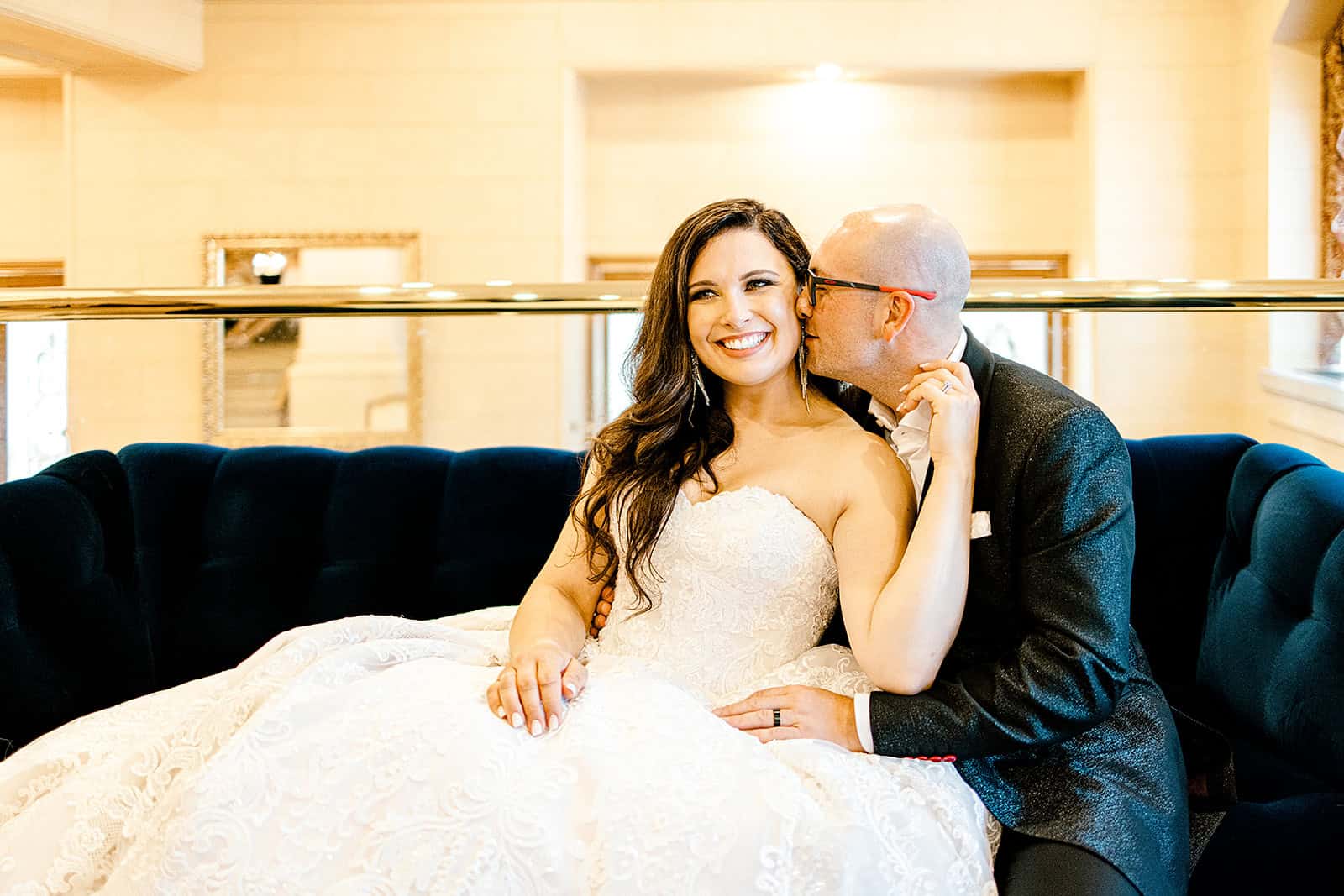 Elegant bride in a lace wedding gown with groom sharing a kiss on the cheek at Winnipeg wedding venue.