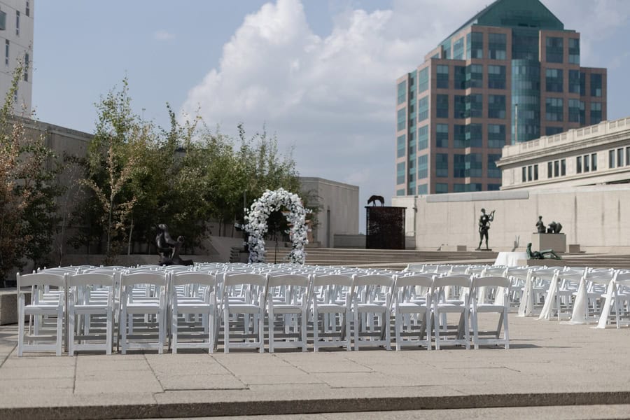 Elegant outdoor wedding ceremony setup with white chairs and floral arch on a city rooftop in Winnipeg.