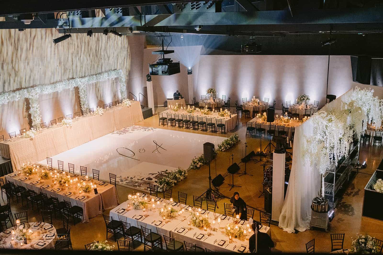 Elegant wedding reception setup with floral arrangements and soft lighting in a spacious banquet hall.