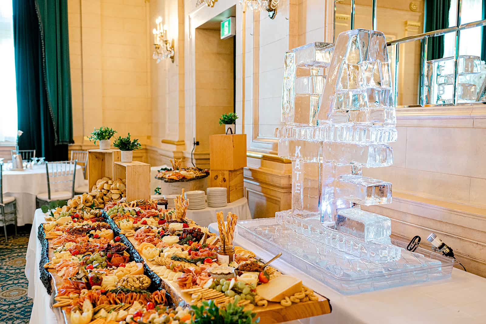 Luxurious wedding reception table with a colorful assortment of cheeses, fruits, and snacks, featuring an elegant ice sculpture display at Melanie Parent Events in Winnipeg.