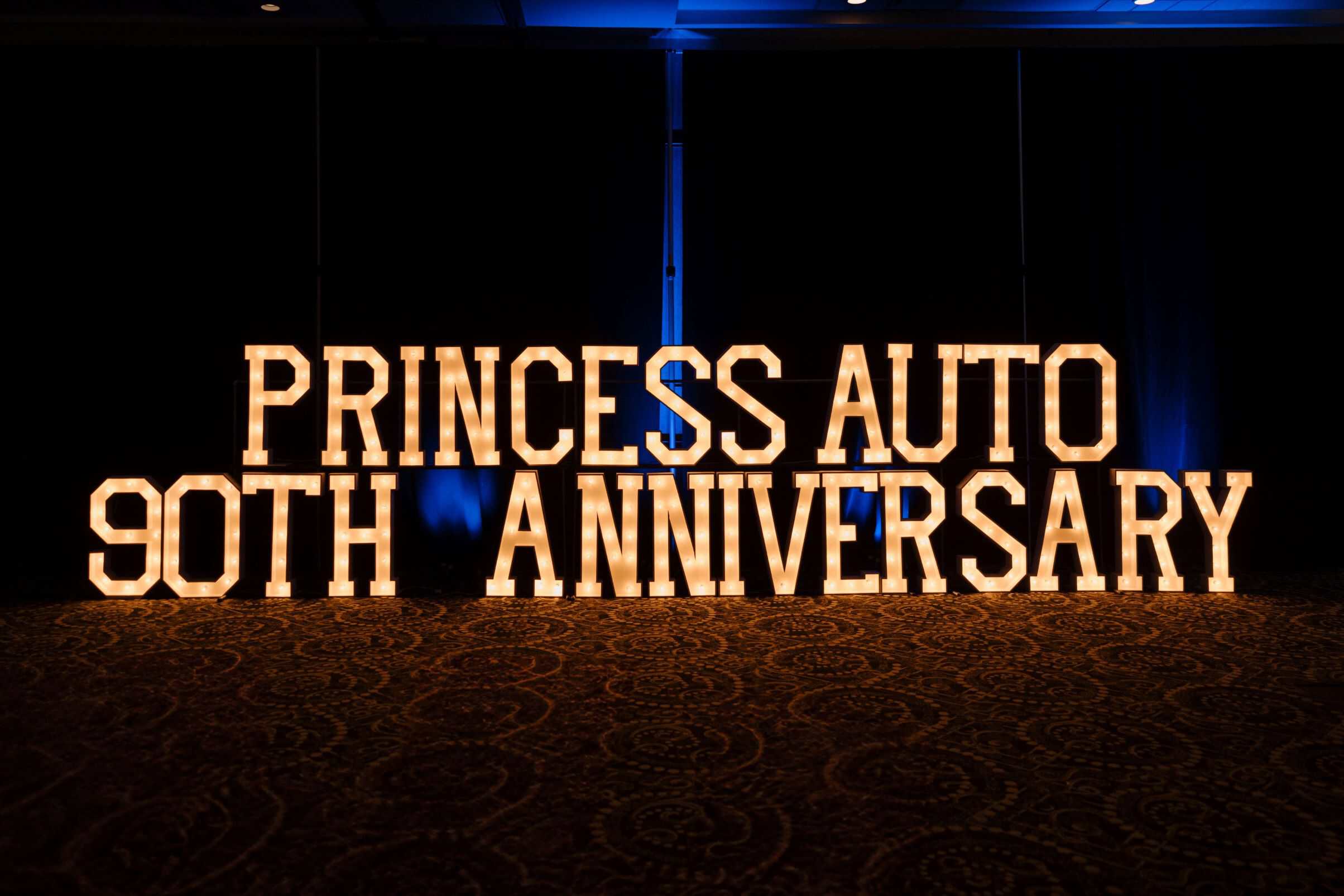 Princess Auto 90th anniversary illuminated marquee sign at an indoor event in Winnipeg, celebrating a milestone with a striking light display.