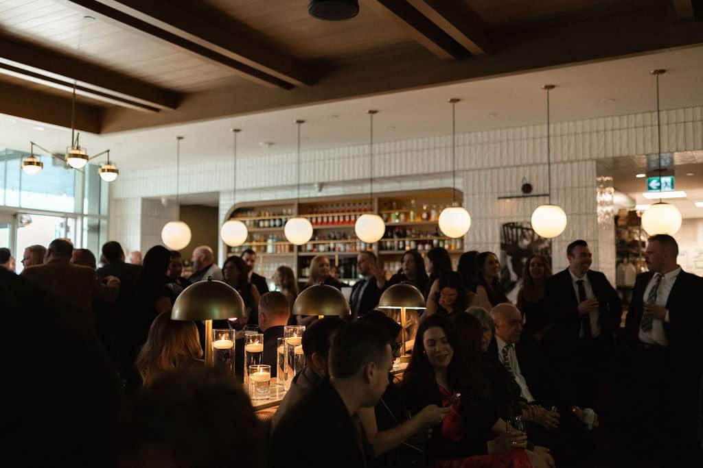 Elegant Winnipeg wedding reception venue with modern lighting and stylish decor, hosting a lively event with guests enjoying food and drinks in a sophisticated atmosphere.