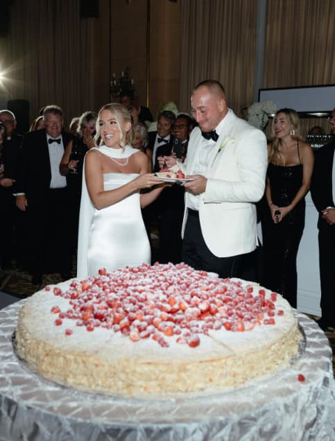 Big wedding cake with strawberries being cut at formal event in Winnipeg, Manitoba.